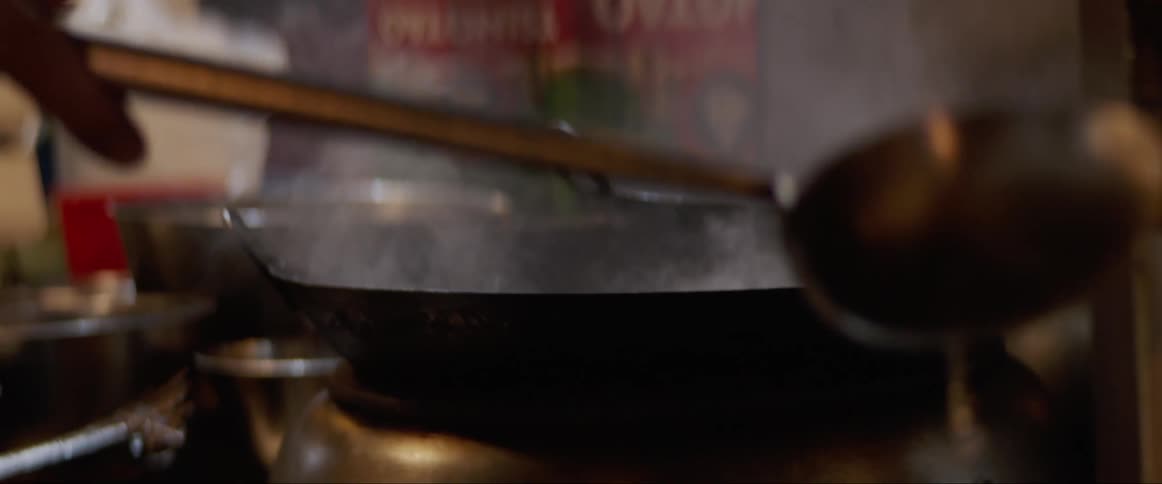 A man spoons liquid into a pan on a stove