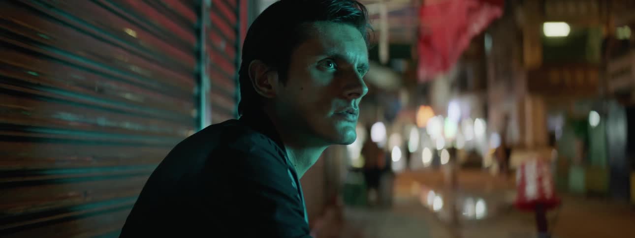 Man wearing leather jacket sitting in the curb of a street in the city at night