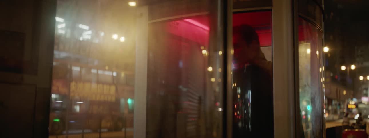 A man stands in a phone booth in a downtown area