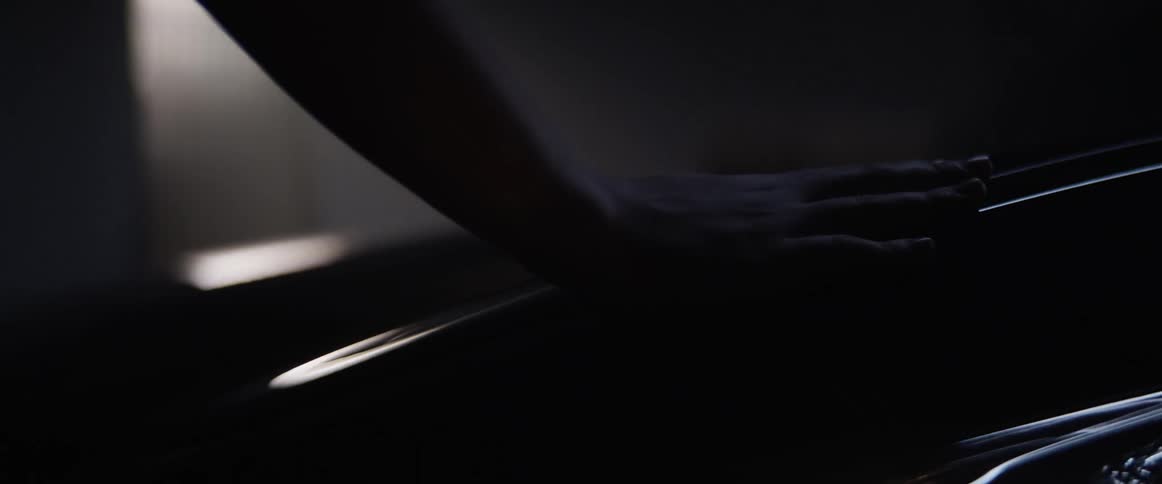 A woman runs her hand along the hood of a car