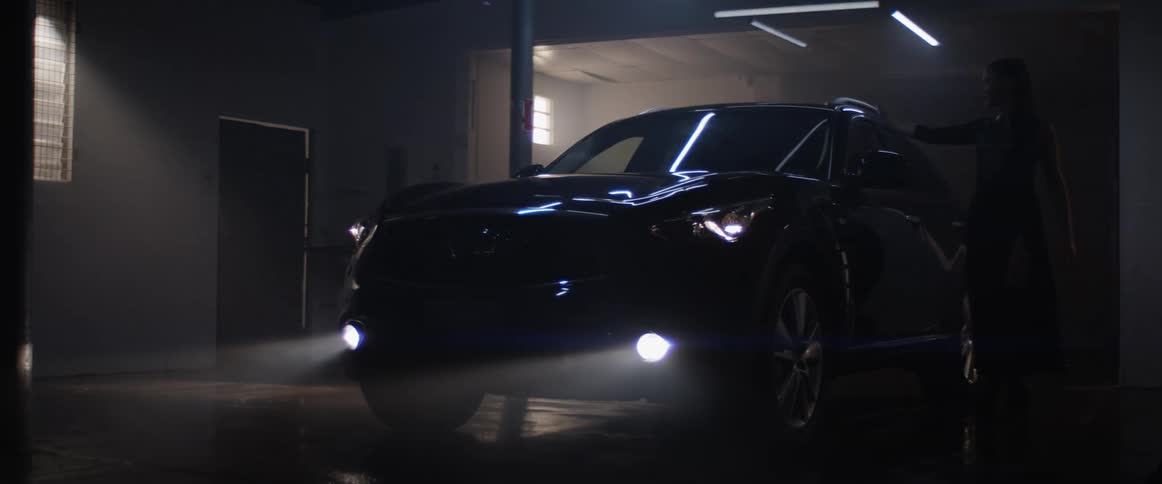 A woman walks past the car touching it