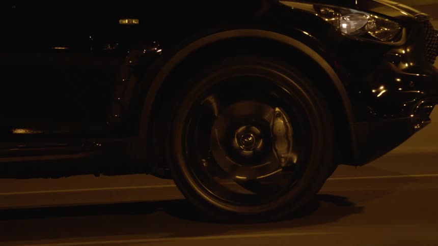 The car is speeding down the road at night