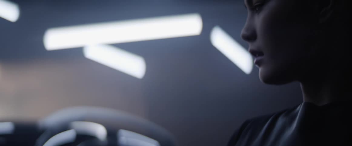 A woman is looking around by a car in the dark room