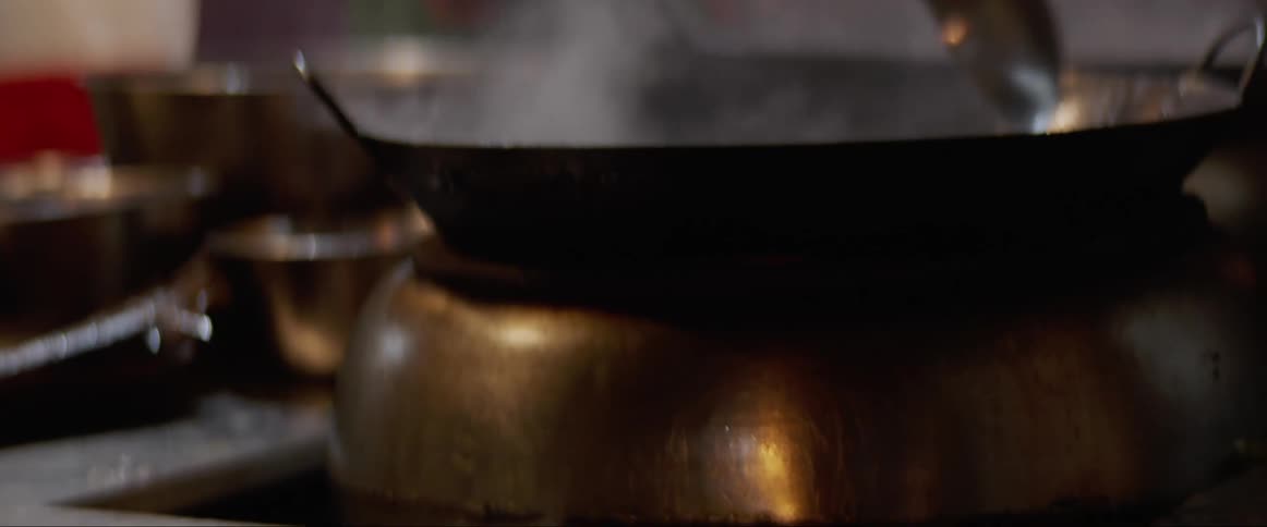 A person pours sauce in a pan and stirs as they cook
