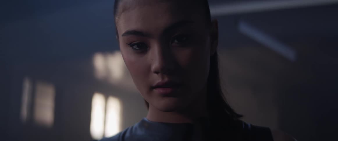 An asian woman looks around a room with flashing fluorescent lights