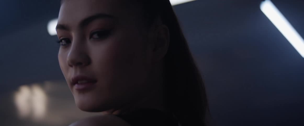 An asian woman stands in a room and looks around by turning her head