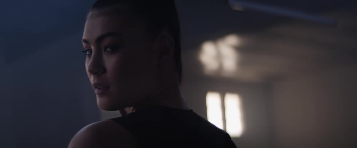 An asian woman walks across a room with her head turned