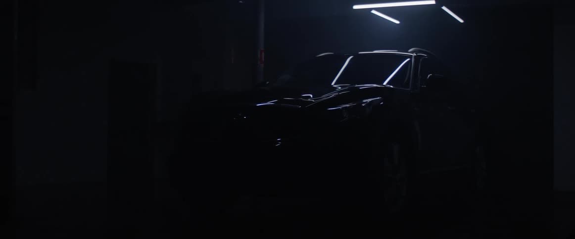 An overhead light flashes and shines down on a parked sport utility vehicle in a parking garage