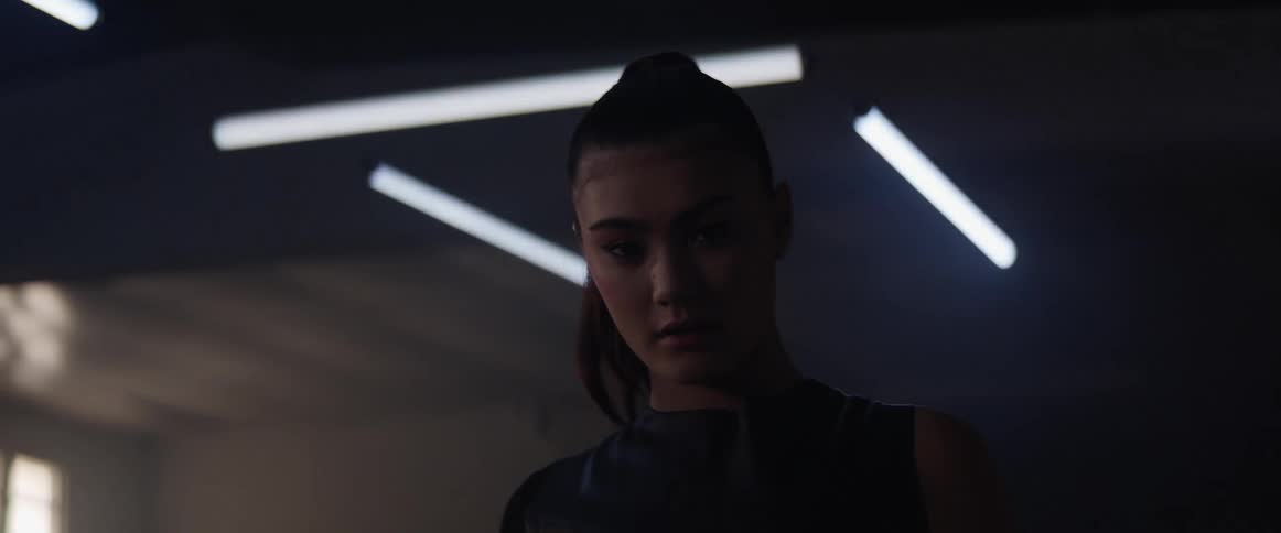 An asian woman stands in a building with flickering lights