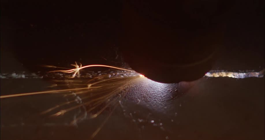 Sparks shoot out from a grinding wheel as it grinds a piece of metal