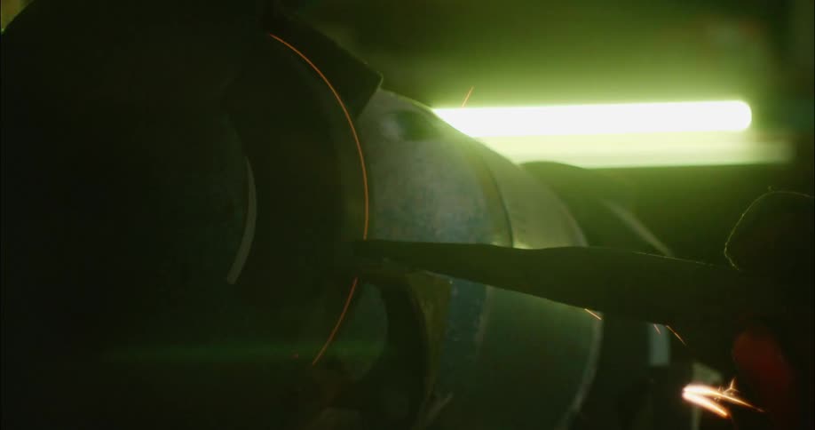 A wheel on a tool turns and sparks fly