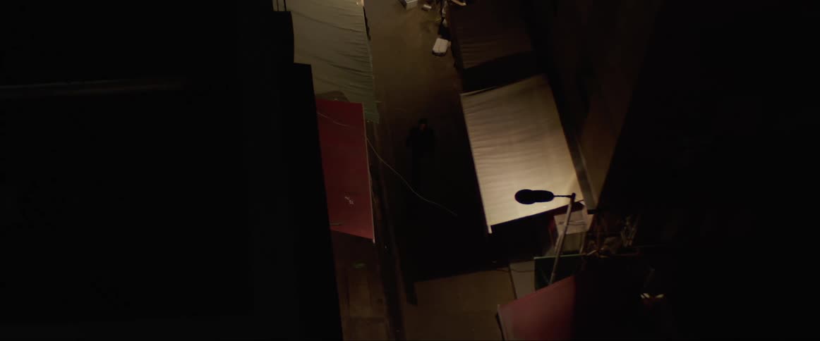 A man walks past store fronts in a city alley at night