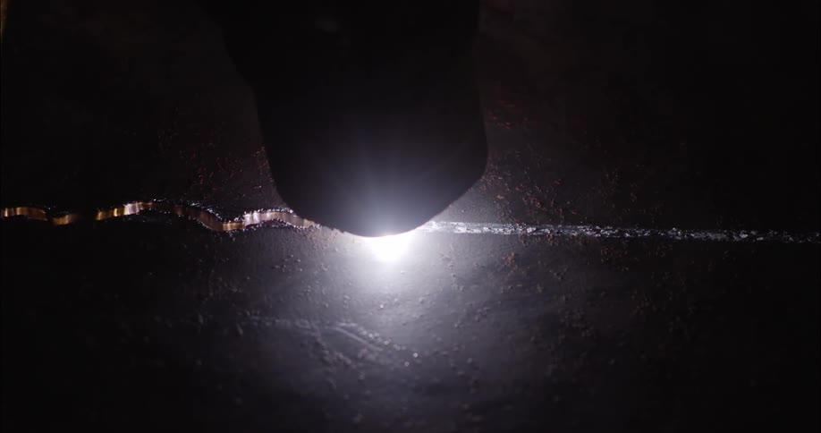 A welding gun cuts a squiggly line through a metal sheet