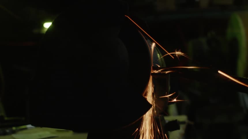 A sharpener throws sparks as it hones a piece of metal