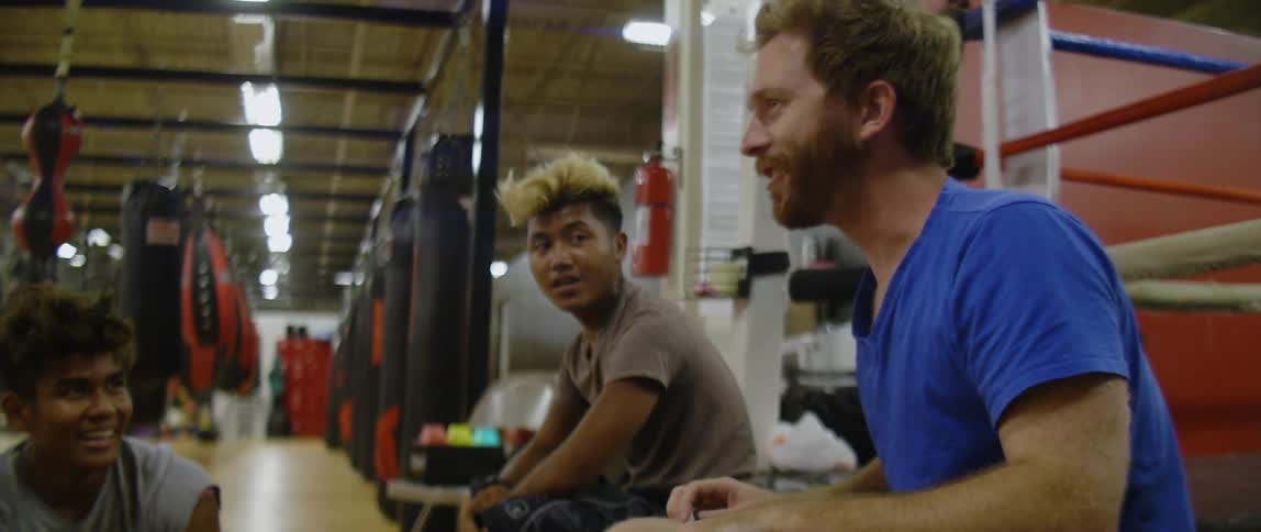A group of guys sit and chat in a gym