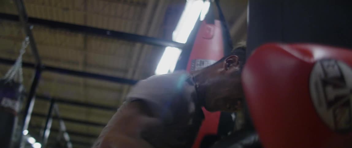 A man is punching the heavy bag held by a sparring partner
