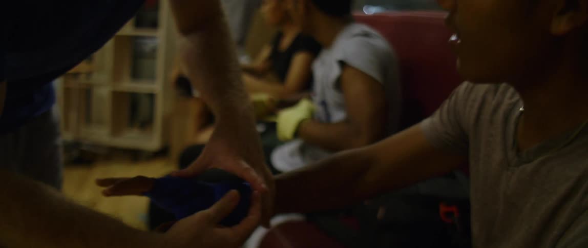 A man wraps a teens hand as others sit and wrap their hands too
