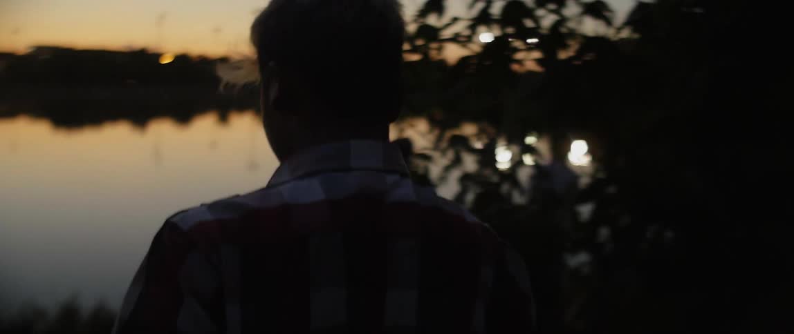Boy walks by the lakeside at dusk