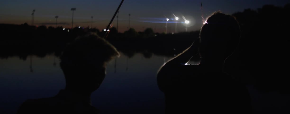 A father and son fish in the lake at dawn
