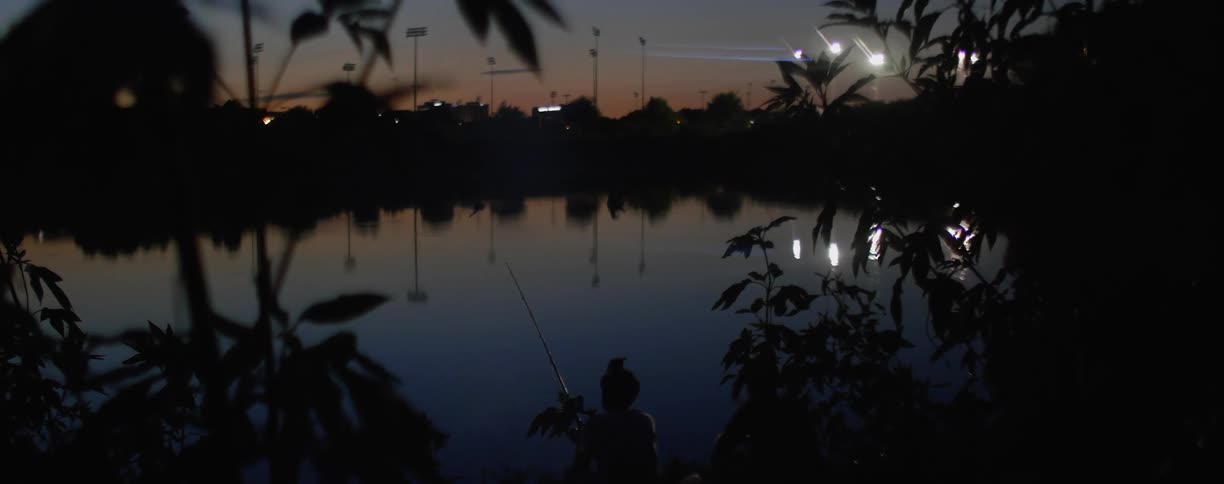 A person fishing at a lake at night