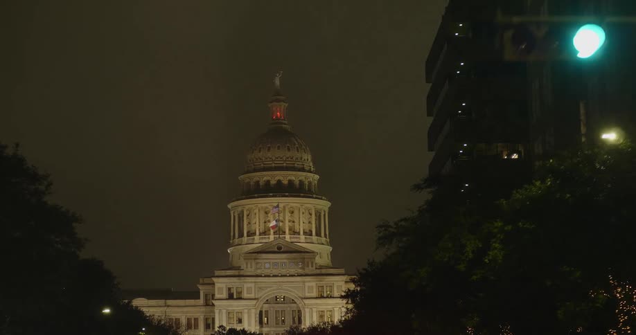 People and cars on a street with a government building