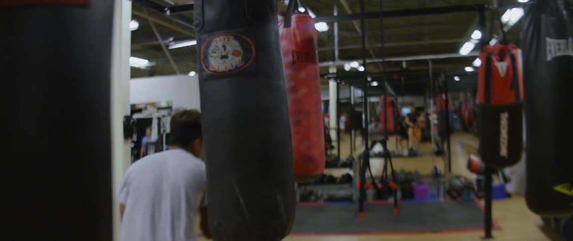 Man trains on a gym dribbling through a course of punching bags