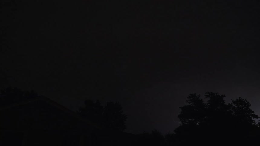Large bolts of lightning light up the night sky over a house