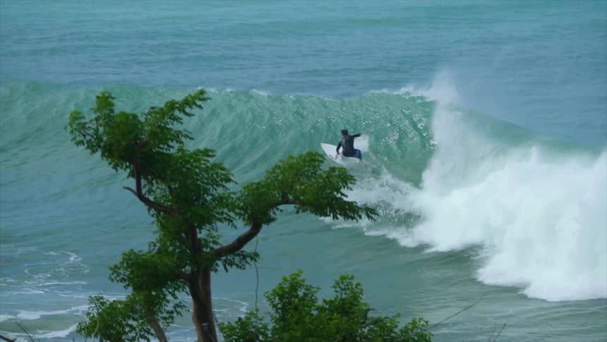 Male surfer rides on a wave in the sea