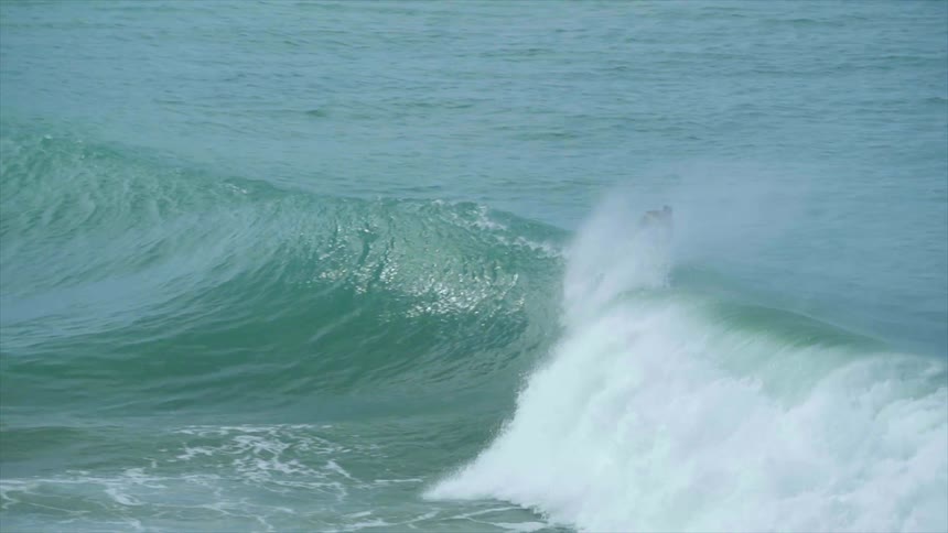 A group of surfers rides on a wave in the sea