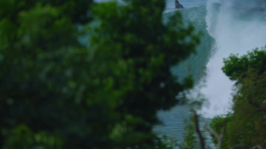 Multiple people ride surfboards on waves in the ocean