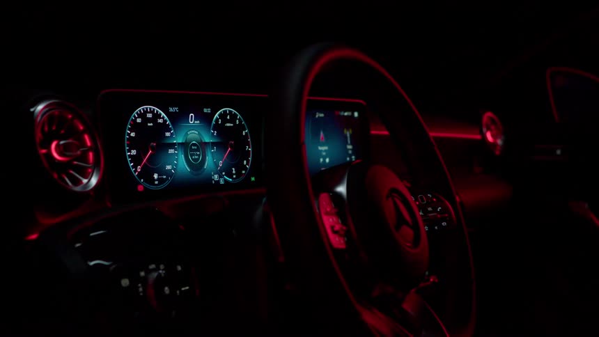 The steering wheel and dashboard of a car all lit up at night