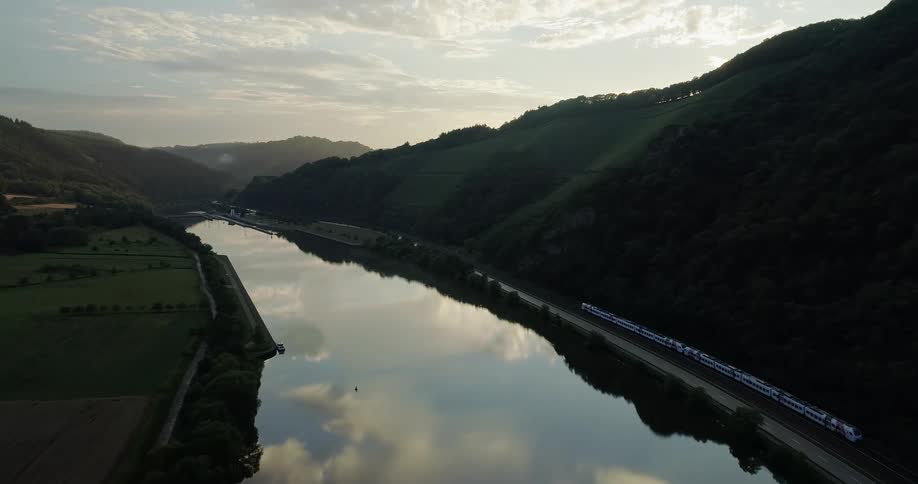 Train travels along metal tracks and carries people by the lake