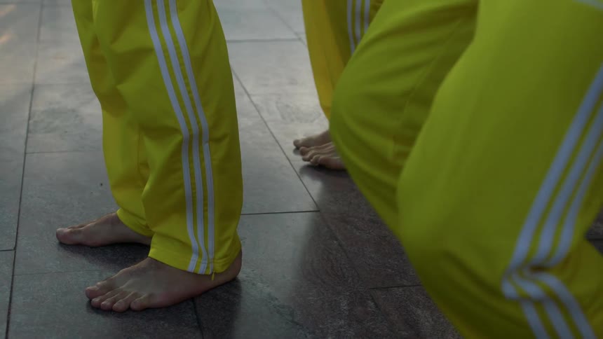 Men in matching yellow and white striped pants practice choreography