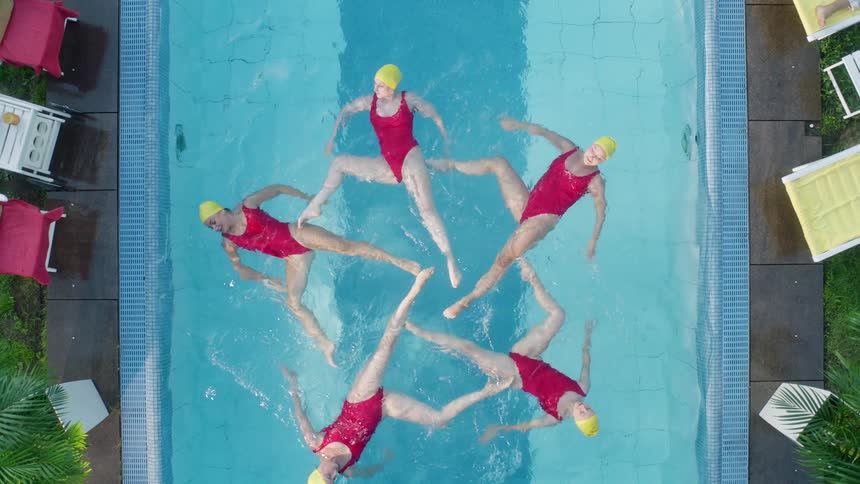 Five teens perform synchronized swimming in a pool