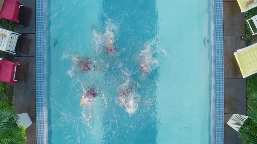 Five women practice synchronized swimming in a pool