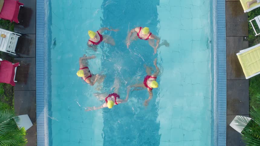 Five women sync their swimming in an outdoor pool