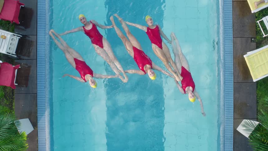 Five women practice synchronized swimming in a pool
