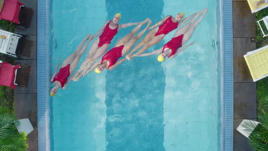 Birds eye view of 5 synchronized swimmers in a pool