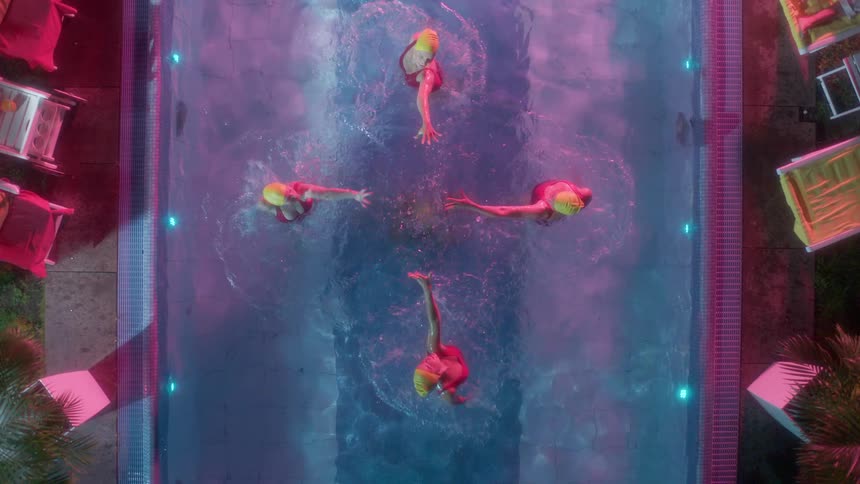 A group of woman do a synchronized swim together in a pool