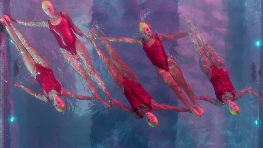 The group of women are performing synchronized swimming together