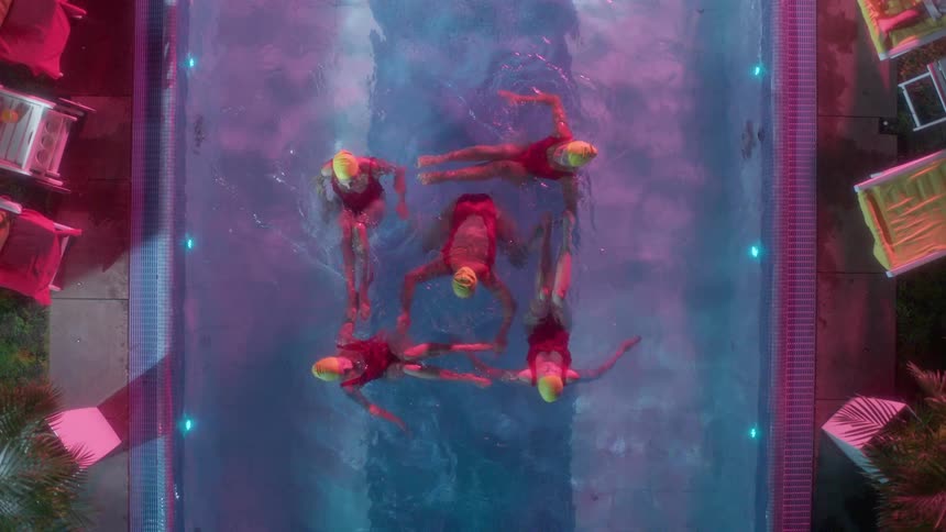 Synchronized swimmers performing a routine in a small outdoor pool at night