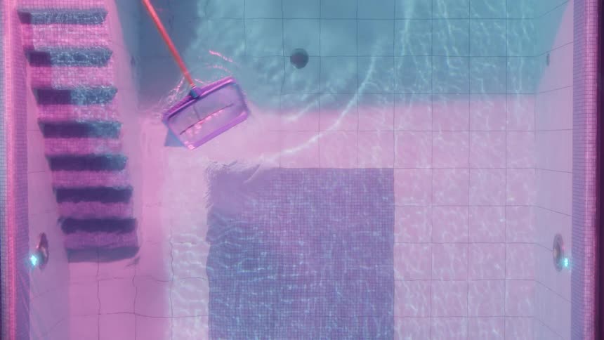 A swimming pool being cleaned by a net on a handle