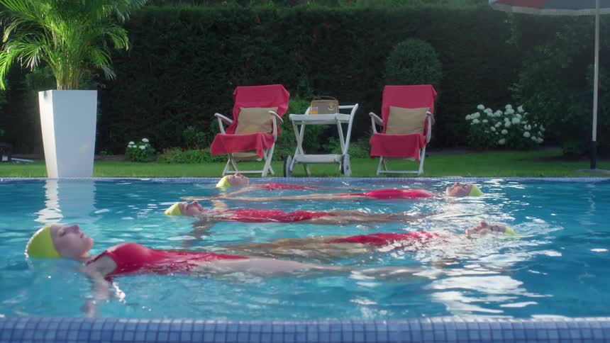 Women practice synchronized swimming in backyard pool