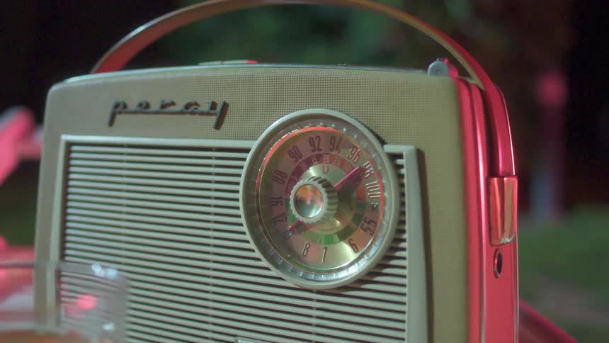 A retro portable radio sits on a table outdoors at night