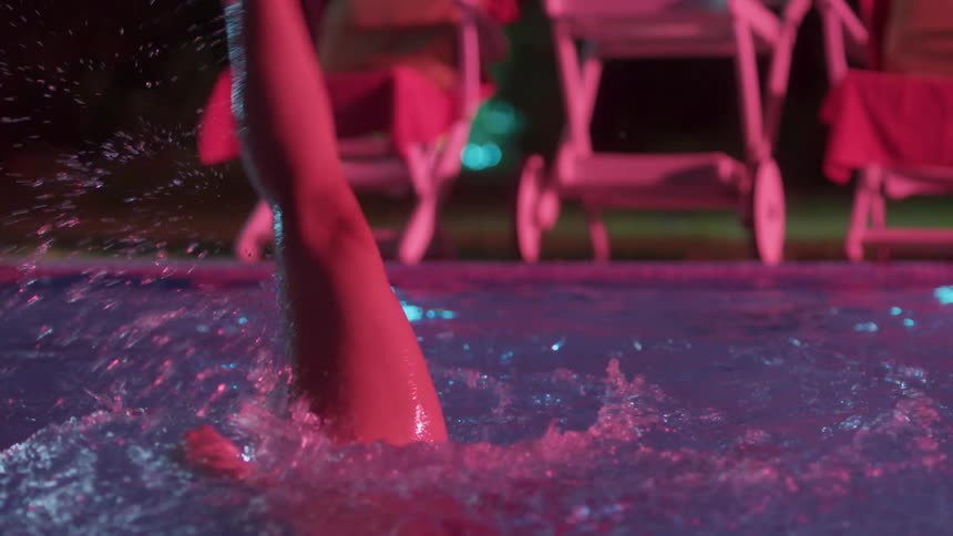 A person swims in the pool at night