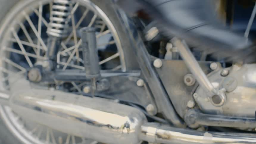 A man wearing boots kick starts a motorcycle