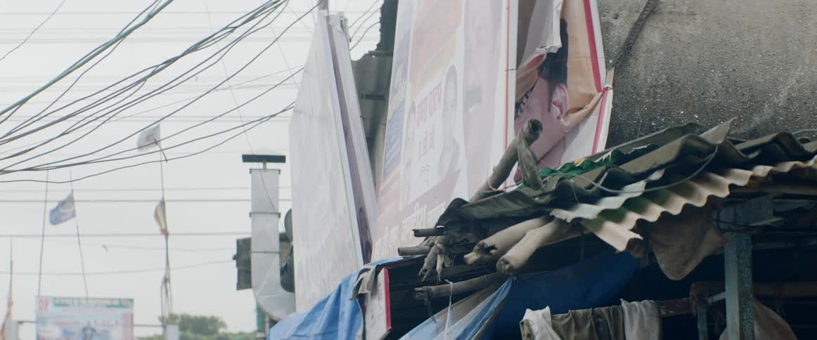 Banners hang near exterior wall near stacked pieces with flags fluttering on flagpoles