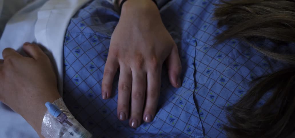 A female patient moves her fingers as she lies in a hospital bed