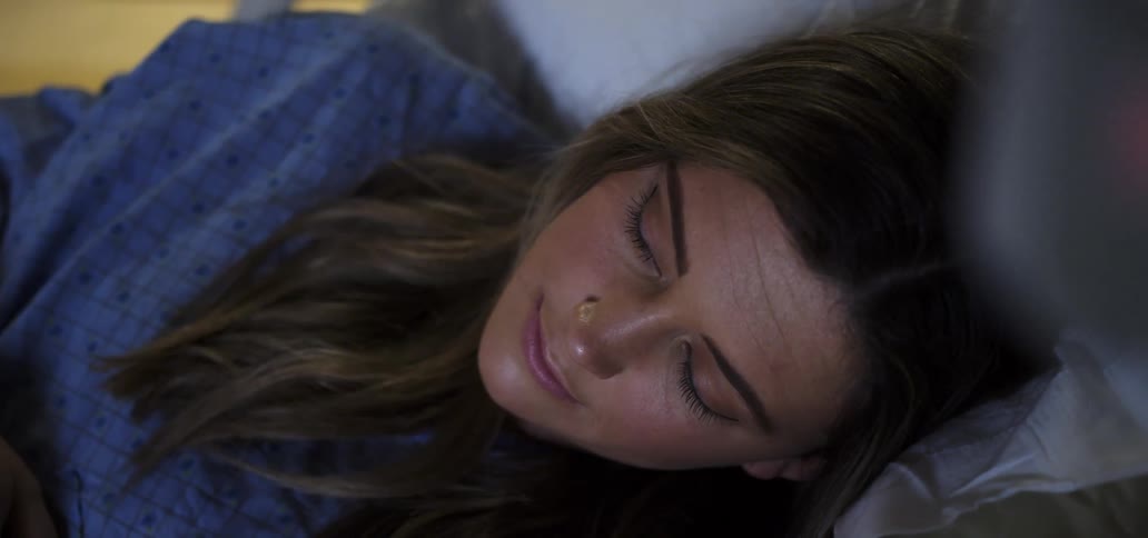 A white woman asleep in a hospital bed