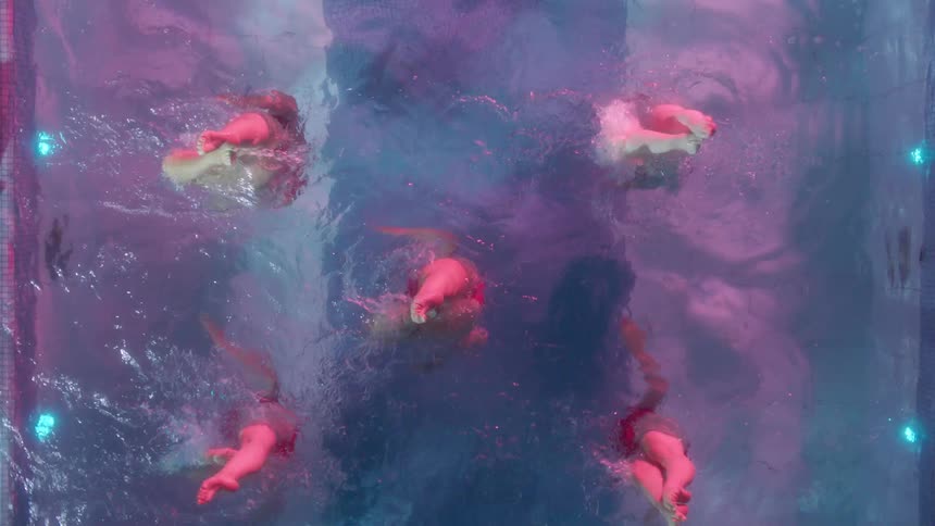 Five women performed synchronized swimming moves in an outdoor pool